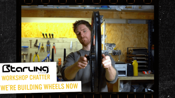 James holding a hand made mountain bike rim, examining if its trued.