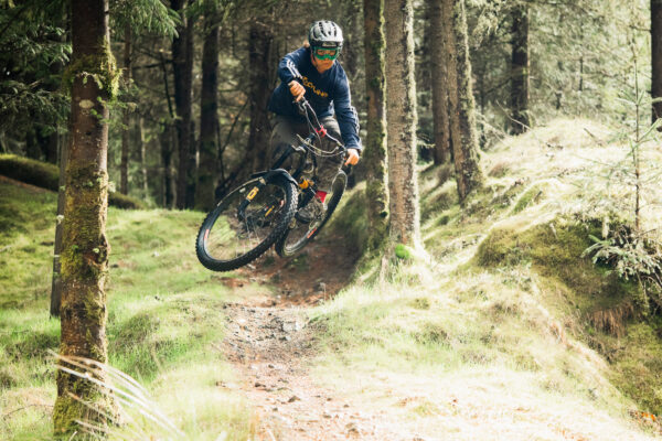Photo of MTB rider jumping towards camera in forest